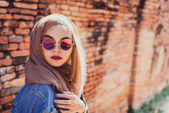 Fashion portrait of young beautiful muslim woman and old brick wall background with copy spaces.